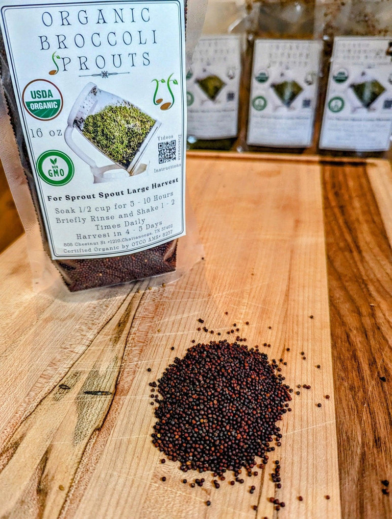 Organic broccoli sprouting seeds on a wooden cutting board next to a 16 oz Sprout Spout seed pouch.